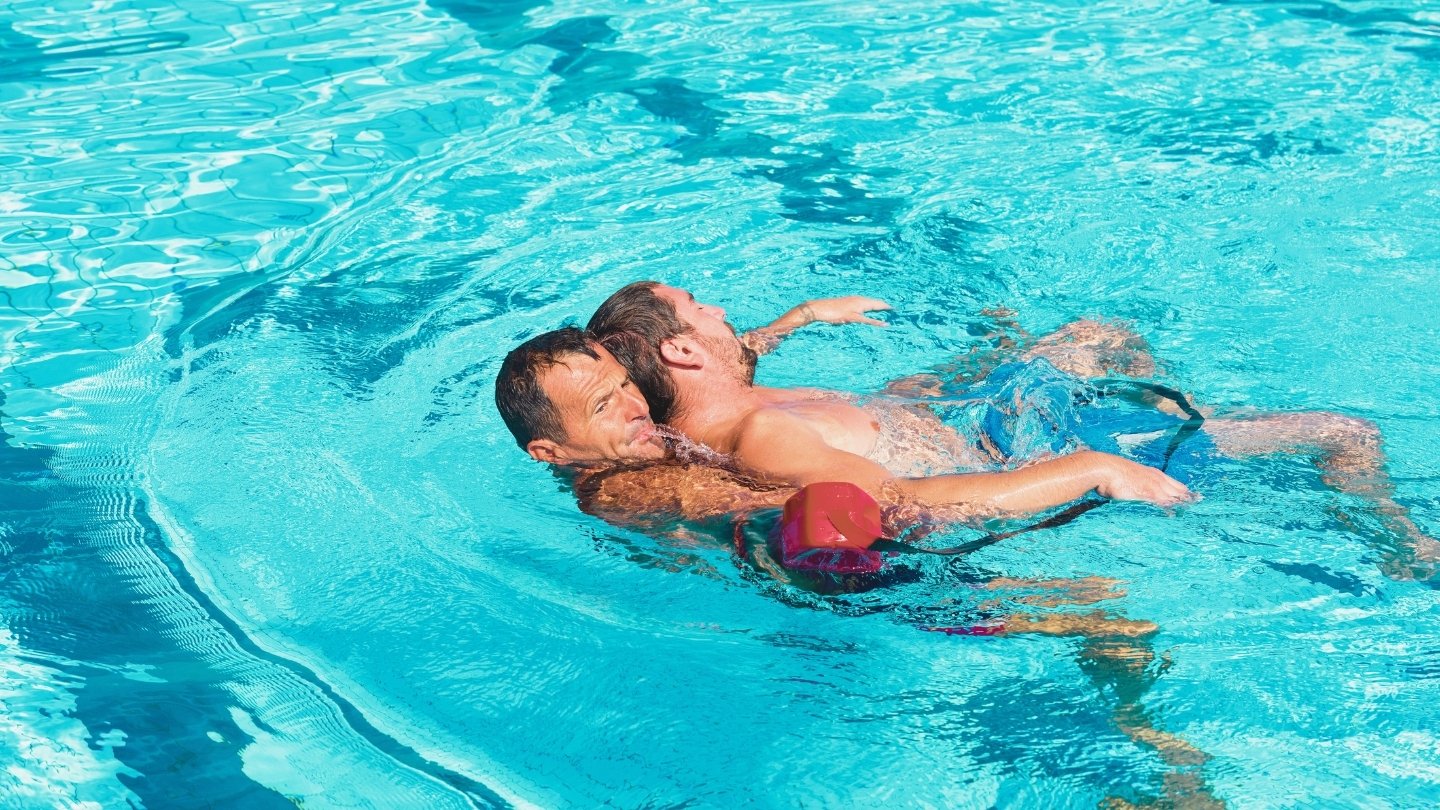 guard rescuing a man in pool